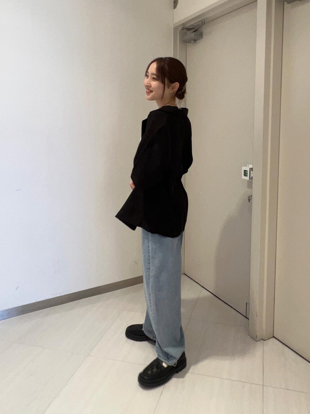 ブルー系のデニムパンツ、ブラック系のローファー、ブラック系のテーラードジャケットを着用したレディースの春コーディネートの3枚目の写真