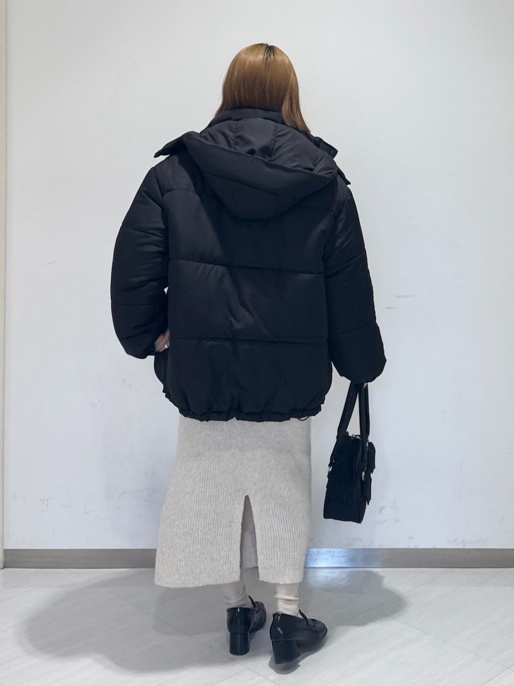 ブラック系のダウンジャケット/コート、イエロー系のニット/セーター、ブラック系のトートバッグを着用したレディースの冬コーディネートの5枚目の写真