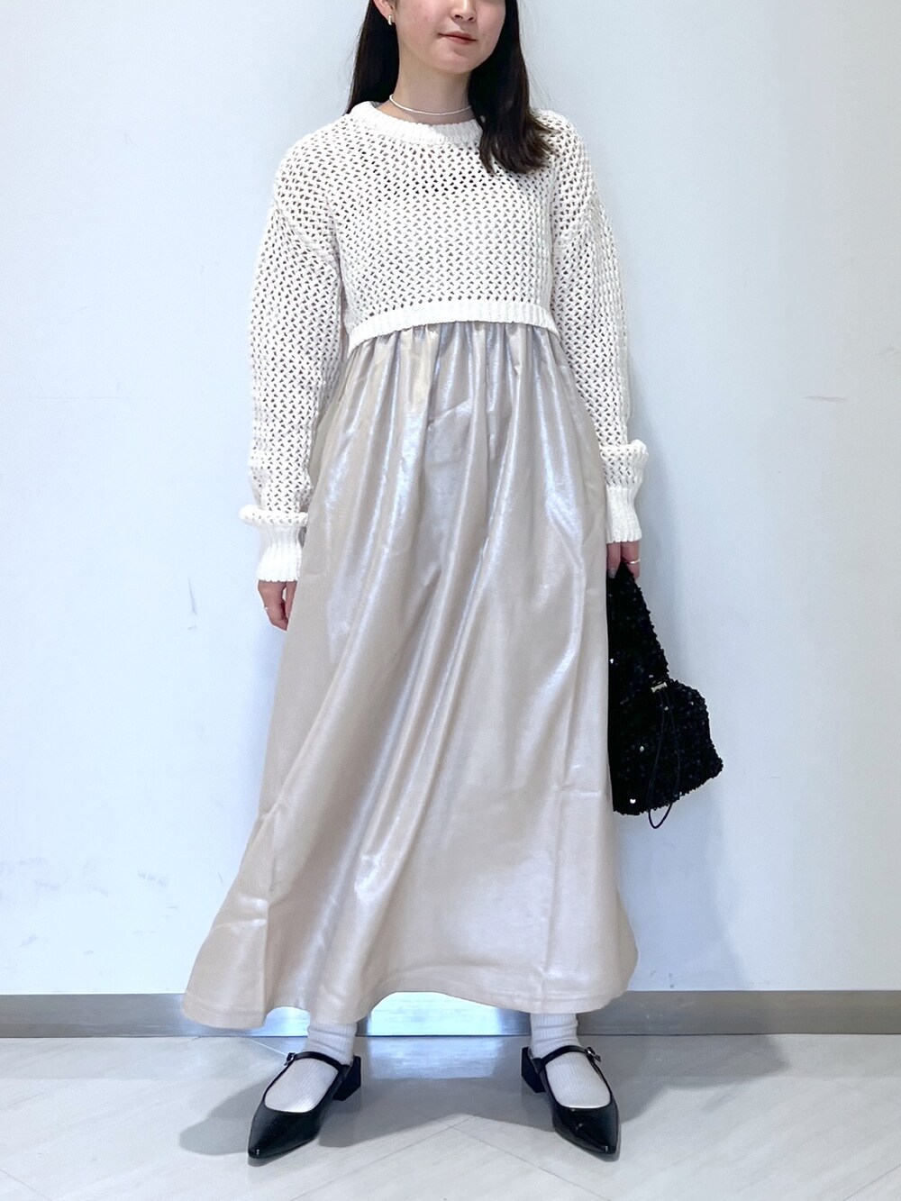 ベージュ系のニット/セーター、ブラック系のハンドバッグ、ベージュ系のワンピースを着用したレディースの春コーディネートの4枚目の写真