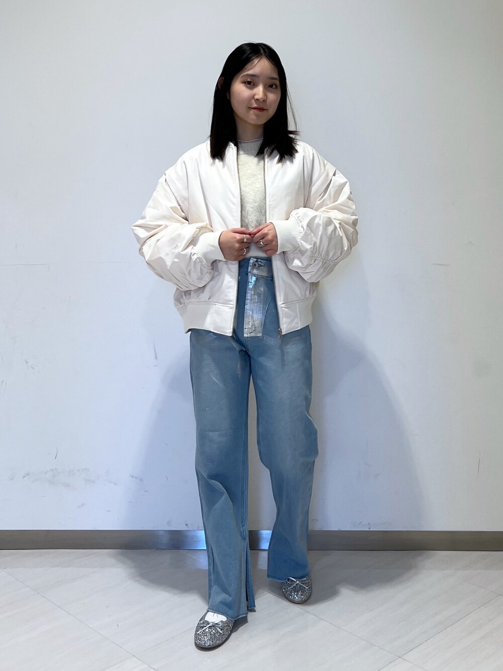 ホワイト系のMA-1、ホワイト系のニット/セーター、ブルー系のデニムパンツを着用したレディースの冬コーディネートの2枚目の写真