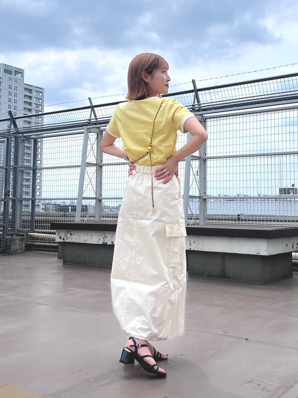 ホワイト系のスカート、イエロー系のTシャツ/カットソー、ブラック系のショルダーバッグを着用したレディースの夏コーディネートの4枚目の写真