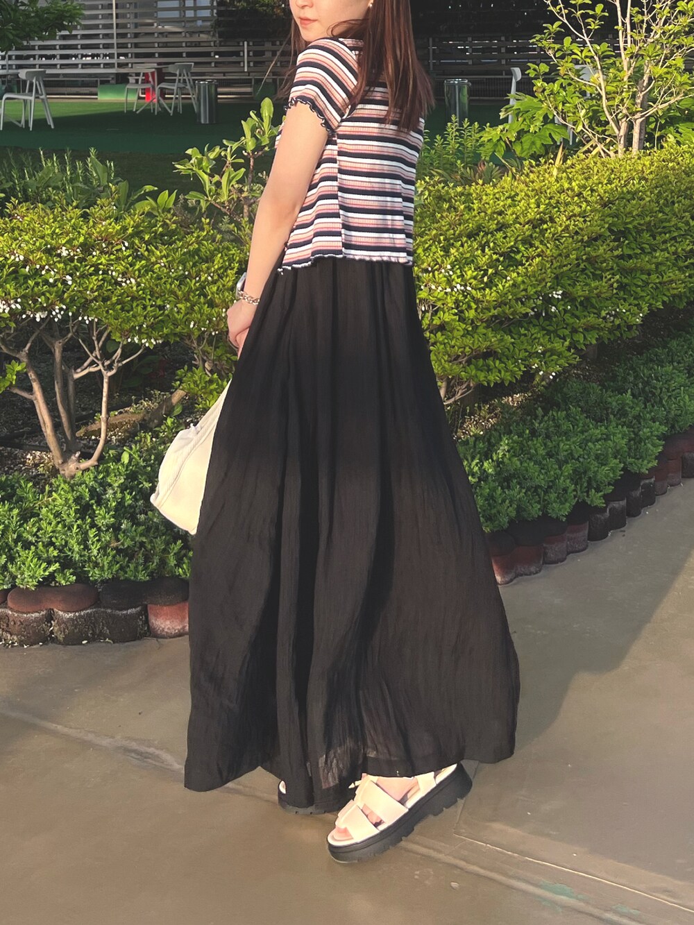 ホワイト系のトートバッグ、ブルー系のTシャツ/カットソー、ブラック系のワンピースを着用したレディースの春コーディネートの3枚目の写真