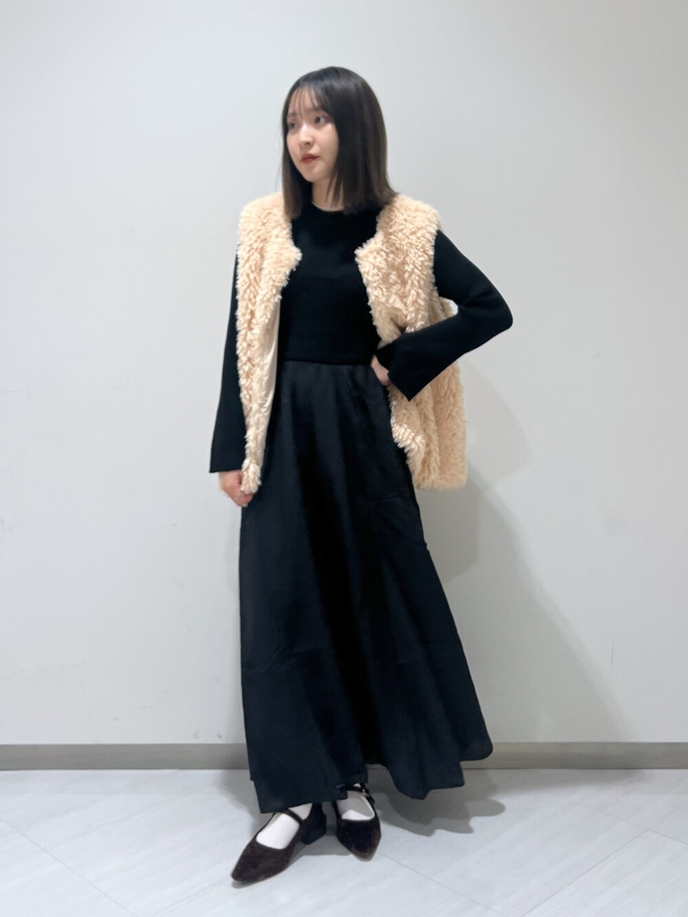 ブラック系のワンピース、ベージュ系のベスト、ブラウン系のバレエシューズを着用したレディースの秋コーディネートの2枚目の写真