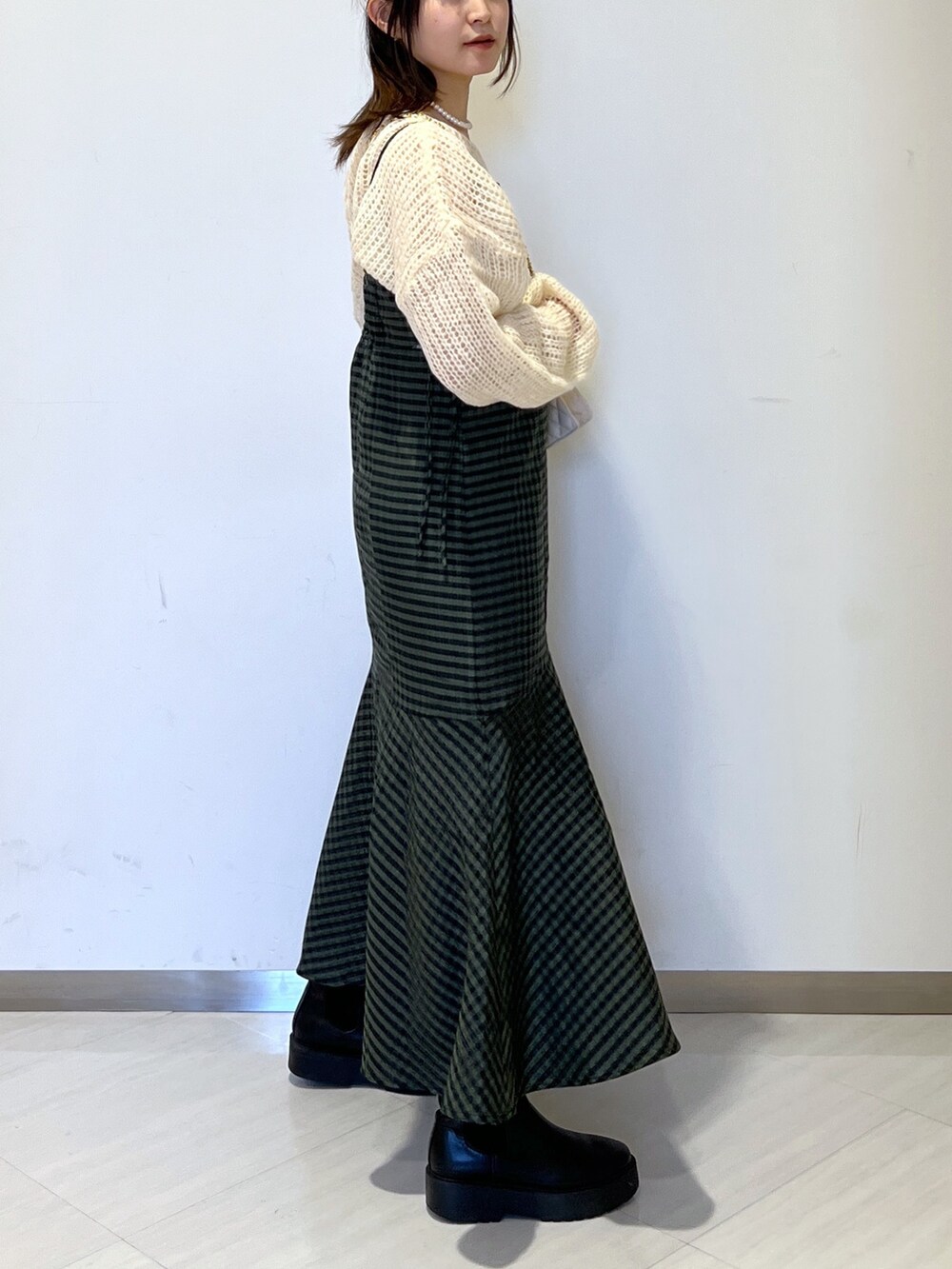 グリーン系のワンピース、ホワイト系のショルダーバッグ、ホワイト系のニット/セーターを着用したレディースの冬コーディネートの4枚目の写真