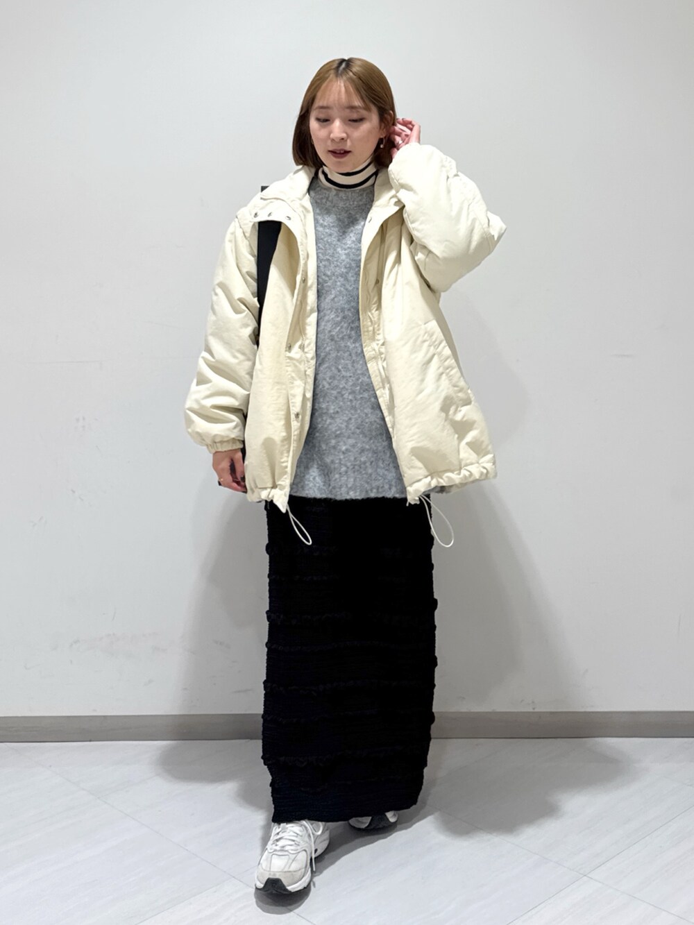 ホワイト系のダウンジャケット/コート、グレー系のニット/セーター、ベージュ系のニット/セーターを着用したレディースの冬コーディネートの2枚目の写真