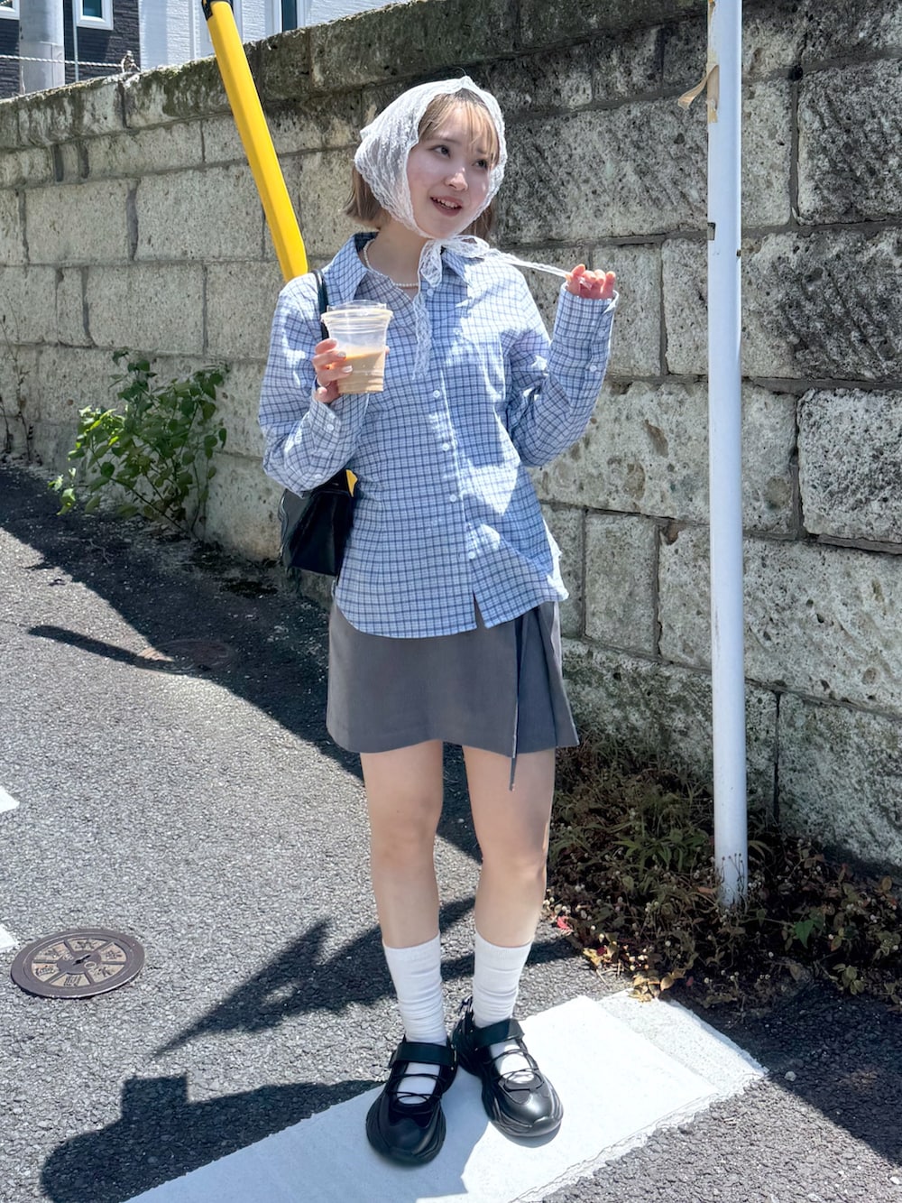 ブルー系のシャツ/ブラウス、グレー系のスカート、ブラック系のスニーカーを着用したレディースの夏コーディネートの3枚目の写真