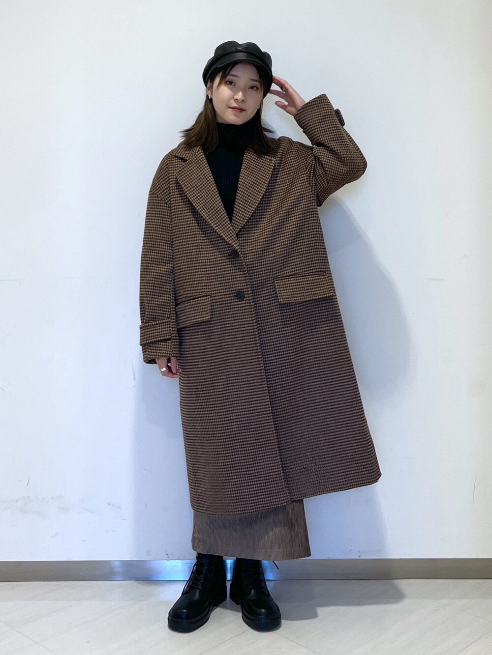 ブラウン系のチェスターコート、ブラック系のニット/セーター、ブラウン系のスカートを着用したレディースの冬コーディネートの2枚目の写真
