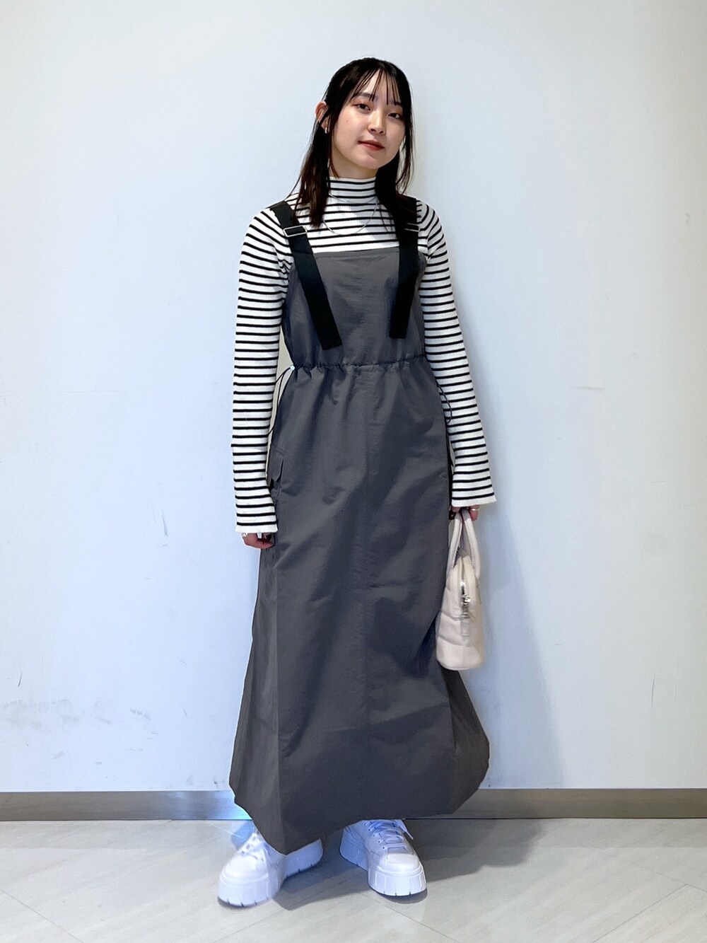 グレー系のワンピース、ホワイト系のハンドバッグ、ホワイト系のニット/セーターを着用したレディースの冬コーディネートの5枚目の写真