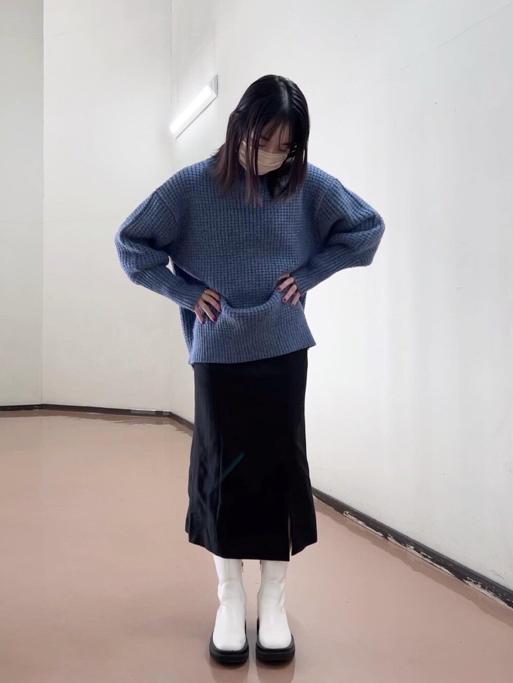 ブルー系のニット/セーター、ブラック系のスカート、ホワイト系のブーツを着用したレディースの秋コーディネートの2枚目の写真