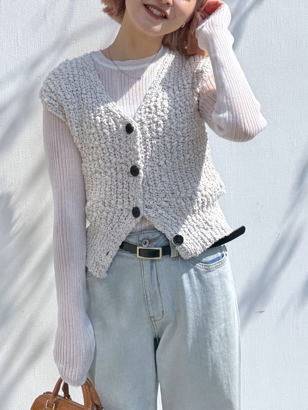 ホワイト系のベスト、ホワイト系のニット/セーター、ブルー系のデニムパンツを着用したレディースの春コーディネートの4枚目の写真