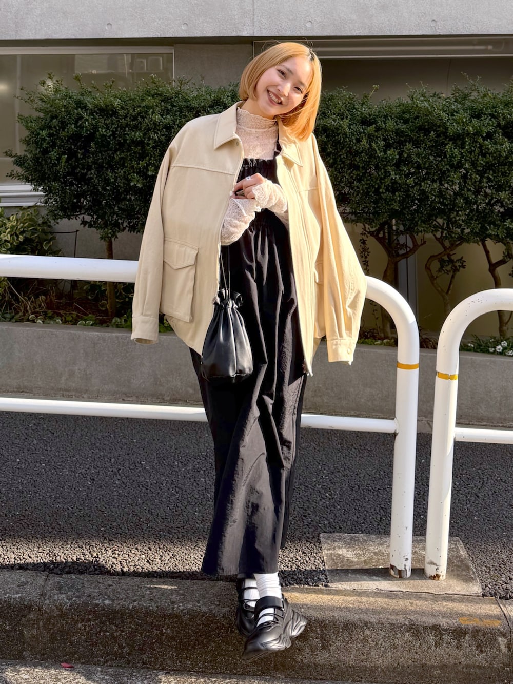 ホワイト系のその他アウター、ホワイト系のTシャツ/カットソー、ブラック系のジャンパースカートを着用したレディースの春コーディネートの2枚目の写真