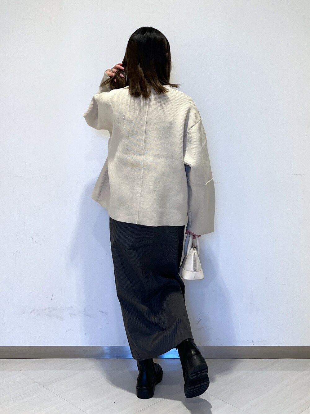 ホワイト系のカーディガン/ボレロ、ブラック系のニット/セーター、ホワイト系のショルダーバッグを着用したレディースの冬コーディネートの5枚目の写真