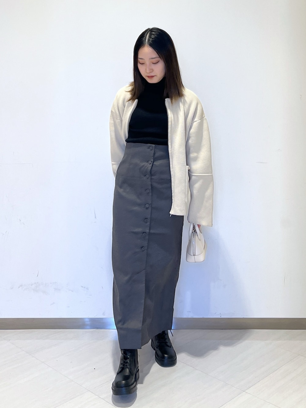 ホワイト系のカーディガン/ボレロ、ブラック系のニット/セーター、ホワイト系のショルダーバッグを着用したレディースの冬コーディネートの3枚目の写真