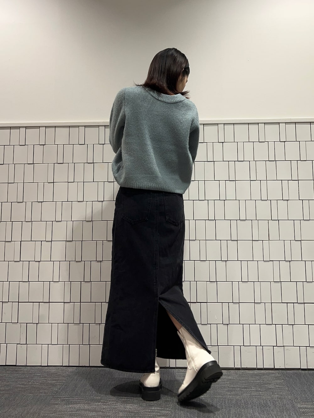 グリーン系のニット/セーター、ブラック系のデニムスカート、ホワイト系のブーツを着用したレディースの冬コーディネートの2枚目の写真