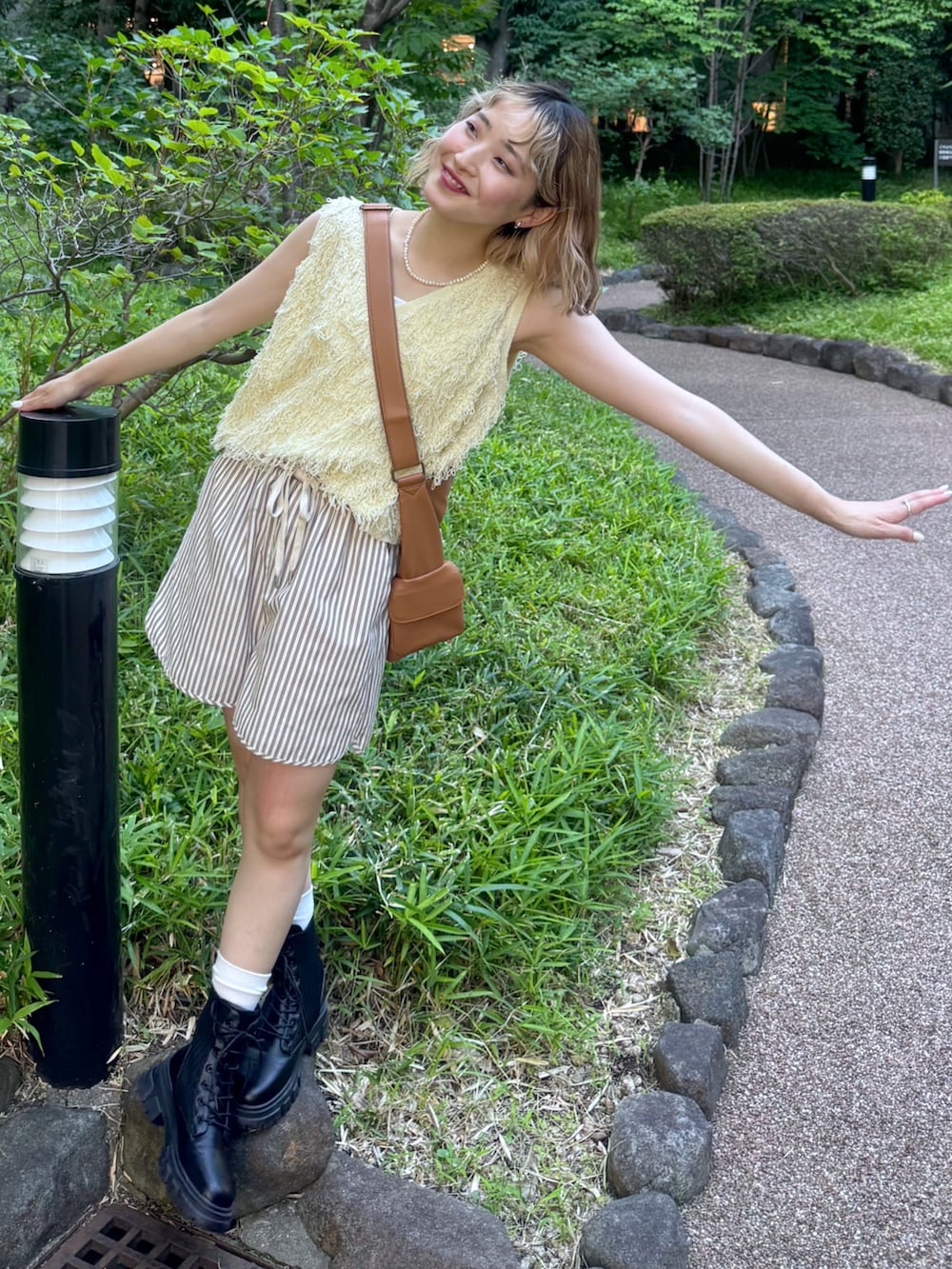 イエロー系のニット/セーター、ブラウン系のトートバッグ、ブラウン系のその他パンツを着用したレディースの夏コーディネートの2枚目の写真