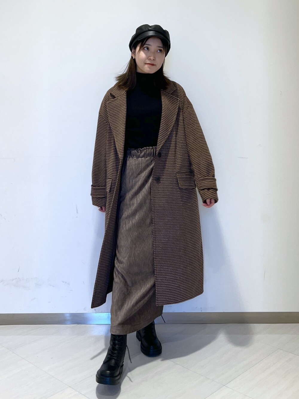 ブラウン系のチェスターコート、ブラック系のニット/セーター、ブラウン系のスカートを着用したレディースの冬コーディネートの3枚目の写真