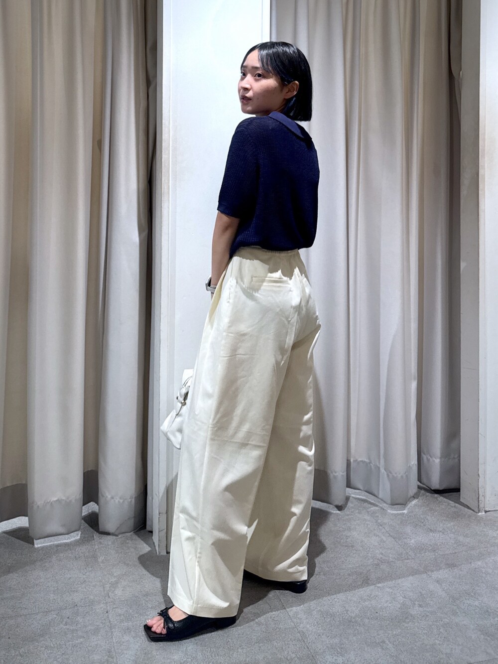 ブルー系のニット/セーター、ホワイト系のスラックス、ホワイト系のショルダーバッグを着用したレディースの夏コーディネートの3枚目の写真