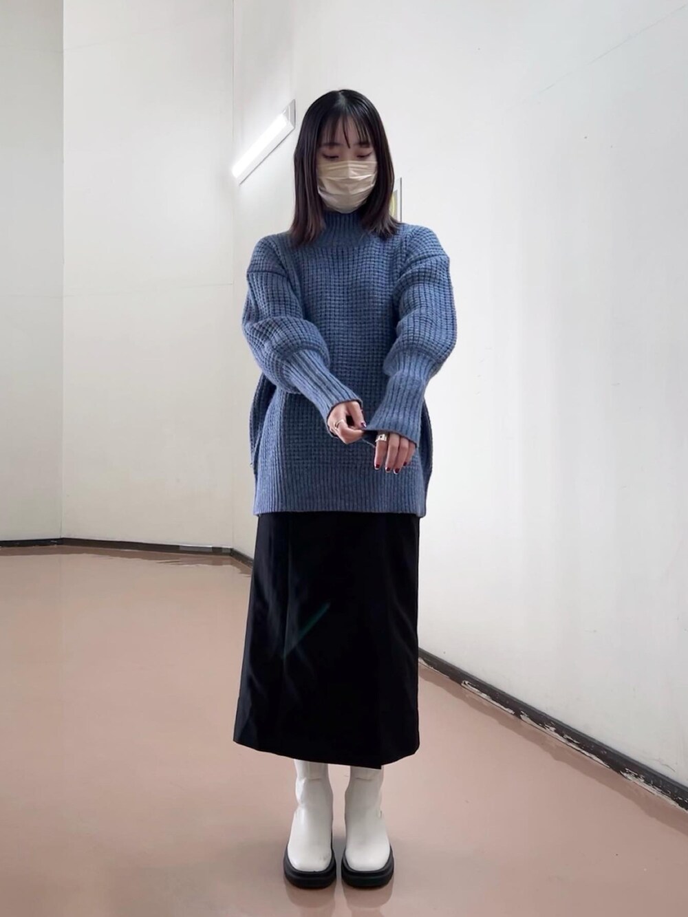 ブルー系のニット/セーター、ブラック系のスカート、ホワイト系のブーツを着用したレディースの秋コーディネートの5枚目の写真