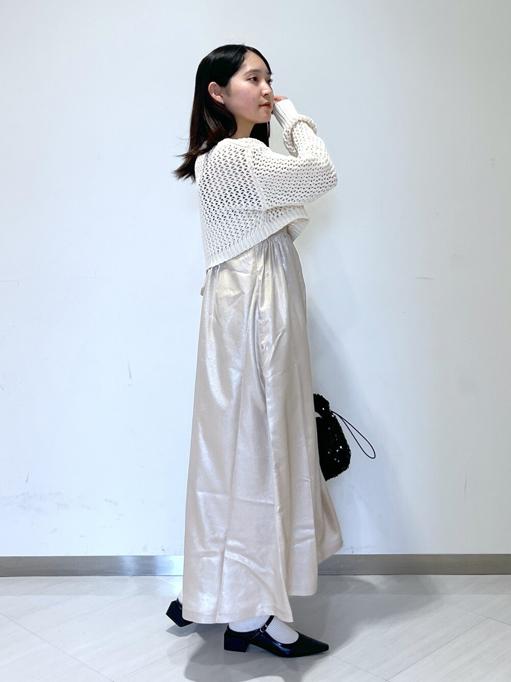 ベージュ系のニット/セーター、ブラック系のハンドバッグ、ベージュ系のワンピースを着用したレディースの春コーディネートの2枚目の写真