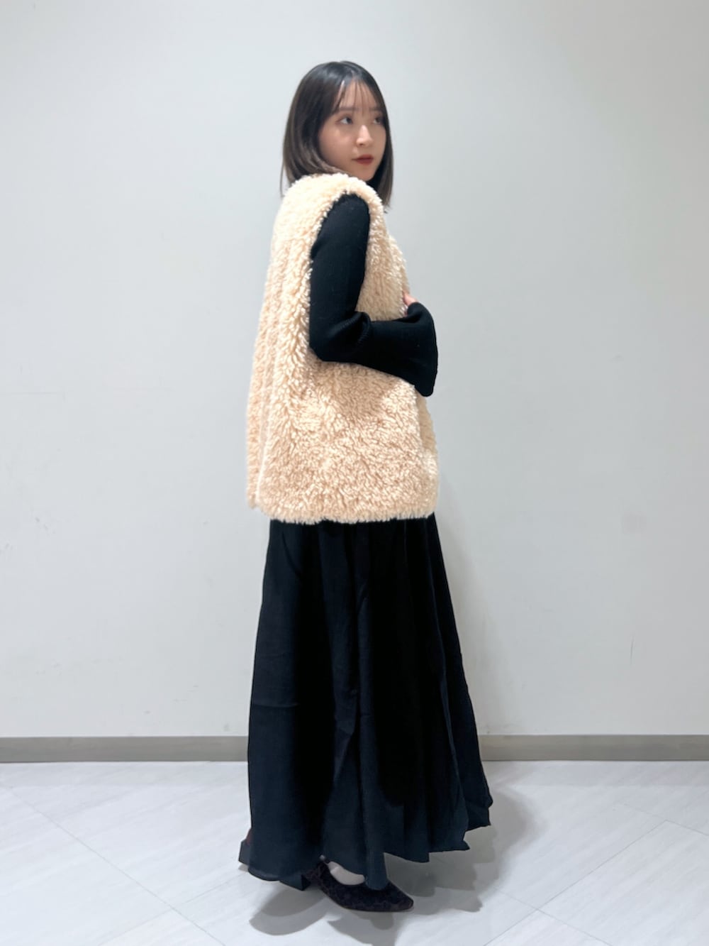 ブラック系のワンピース、ベージュ系のベスト、ブラウン系のバレエシューズを着用したレディースの秋コーディネートの3枚目の写真