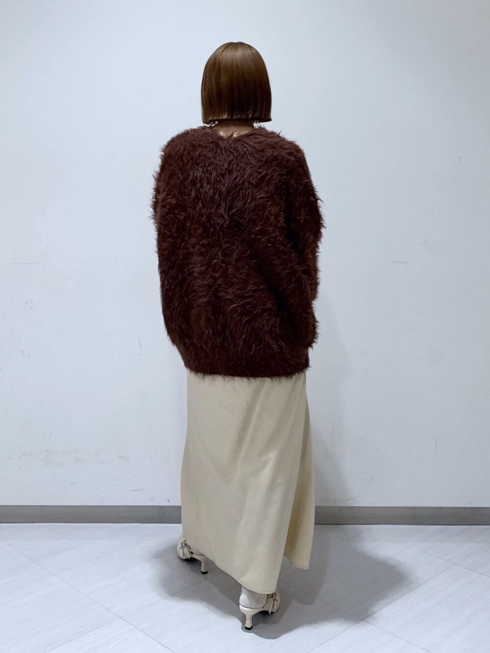 ブラウン系のカーディガン/ボレロ、ホワイト系のタンクトップ、ベージュ系のスカートを着用したレディースの冬コーディネートの5枚目の写真