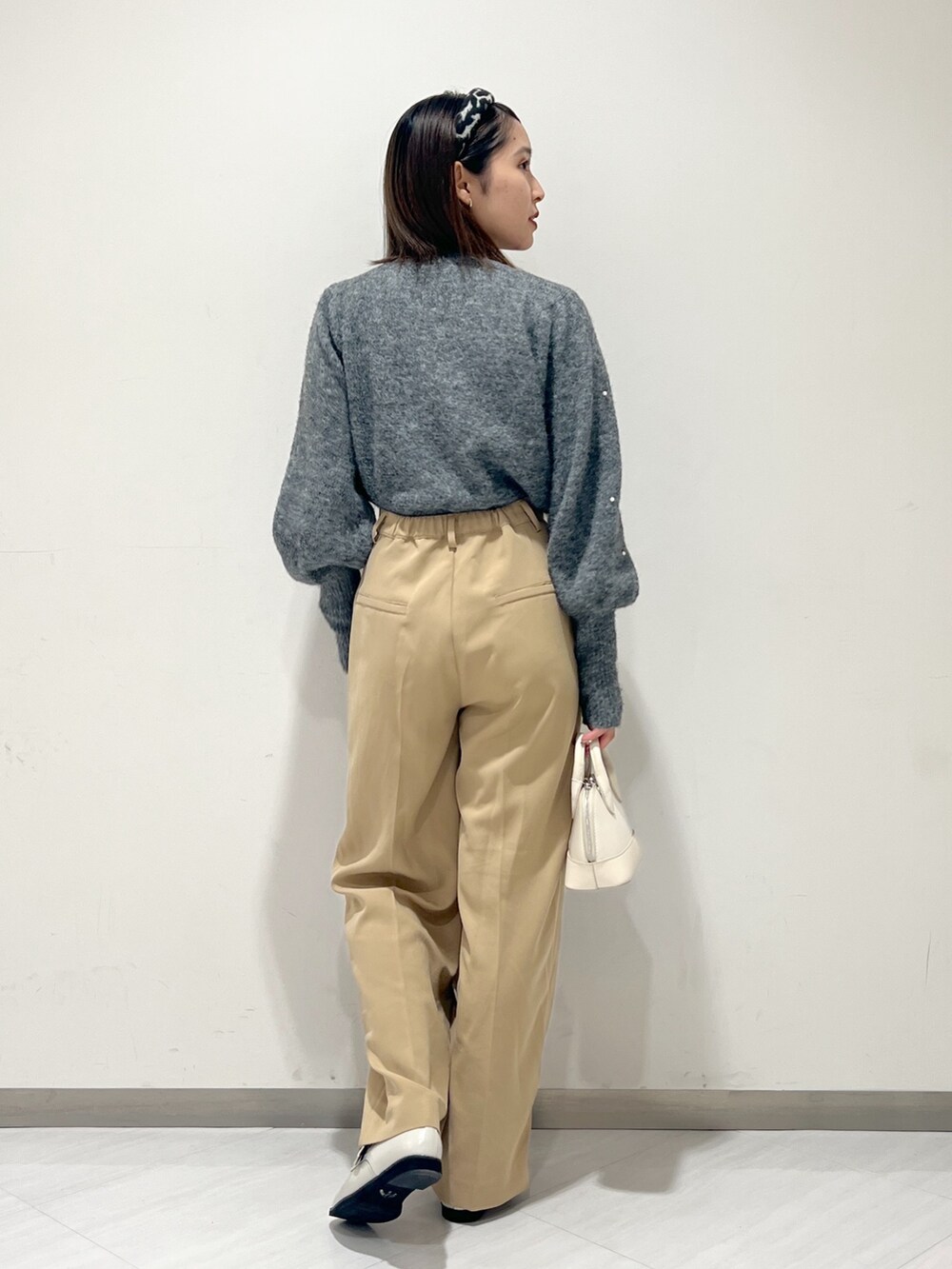 ベージュ系のスラックス、グレー系のニット/セーター、ホワイト系のショルダーバッグを着用したレディースの秋コーディネートの5枚目の写真