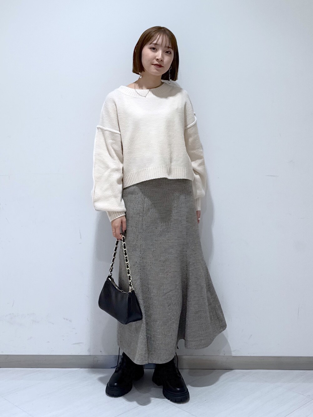 ホワイト系のニット/セーター、ブラック系のトートバッグ、ベージュ系のスカートを着用したレディースの冬コーディネートの4枚目の写真