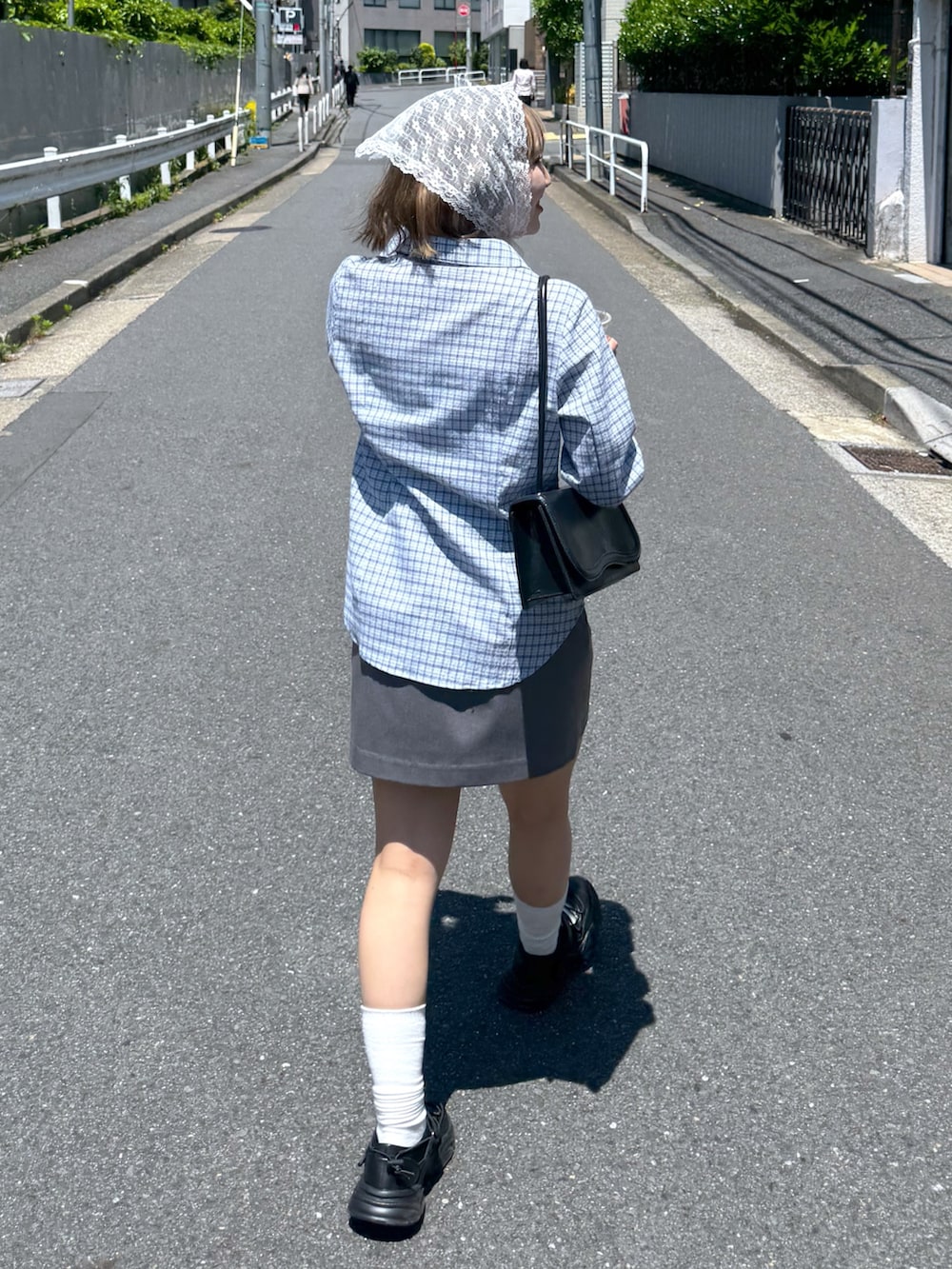 ブルー系のシャツ/ブラウス、グレー系のスカート、ブラック系のスニーカーを着用したレディースの夏コーディネートの5枚目の写真