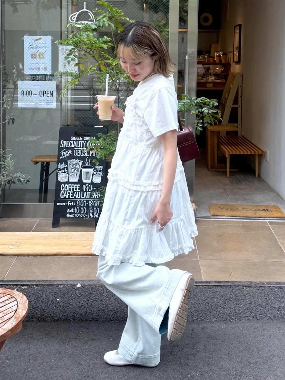 ホワイト系のワンピース、ホワイト系のTシャツ/カットソー、ブルー系のデニムパンツを着用したレディースの夏コーディネートの3枚目の写真