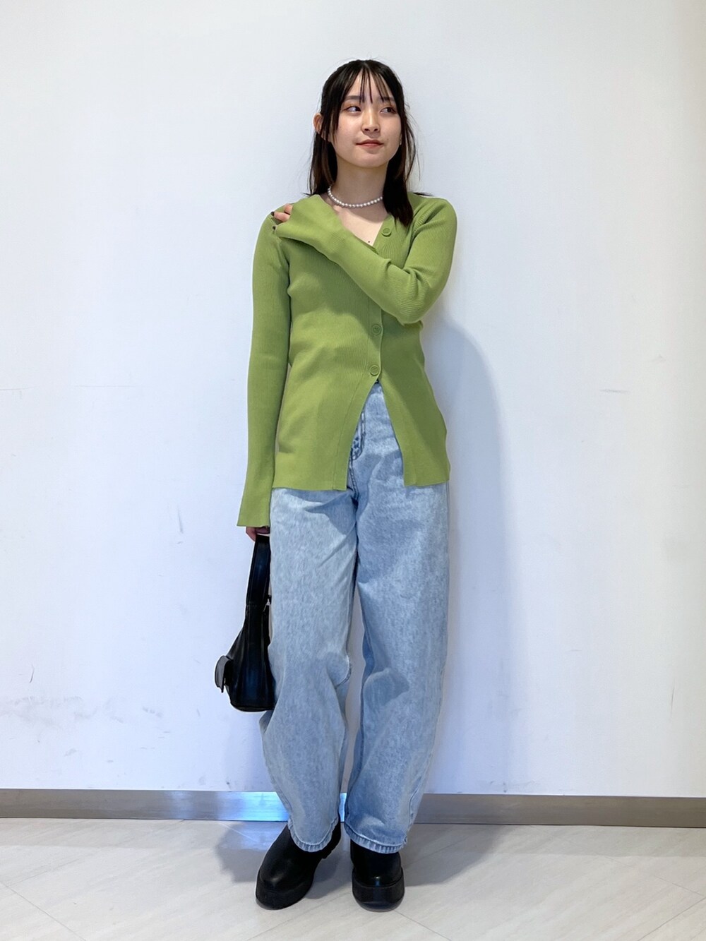 グリーン系のカーディガン/ボレロ、ブラック系のショルダーバッグ、ブルー系のデニムパンツを着用したレディースの冬コーディネートの4枚目の写真