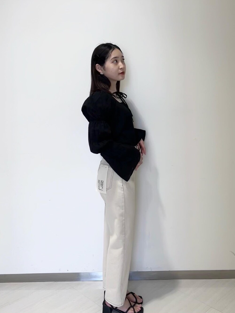 ブラック系のニット/セーター、ブラック系のカーディガン/ボレロ、ホワイト系のデニムパンツを着用したレディースの春コーディネートの4枚目の写真