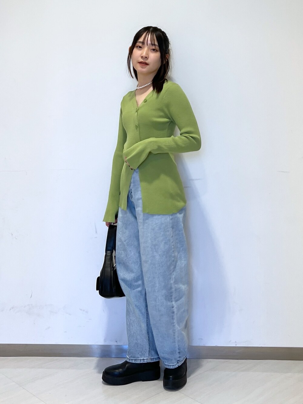 グリーン系のカーディガン/ボレロ、ブラック系のショルダーバッグ、ブルー系のデニムパンツを着用したレディースの冬コーディネートの3枚目の写真