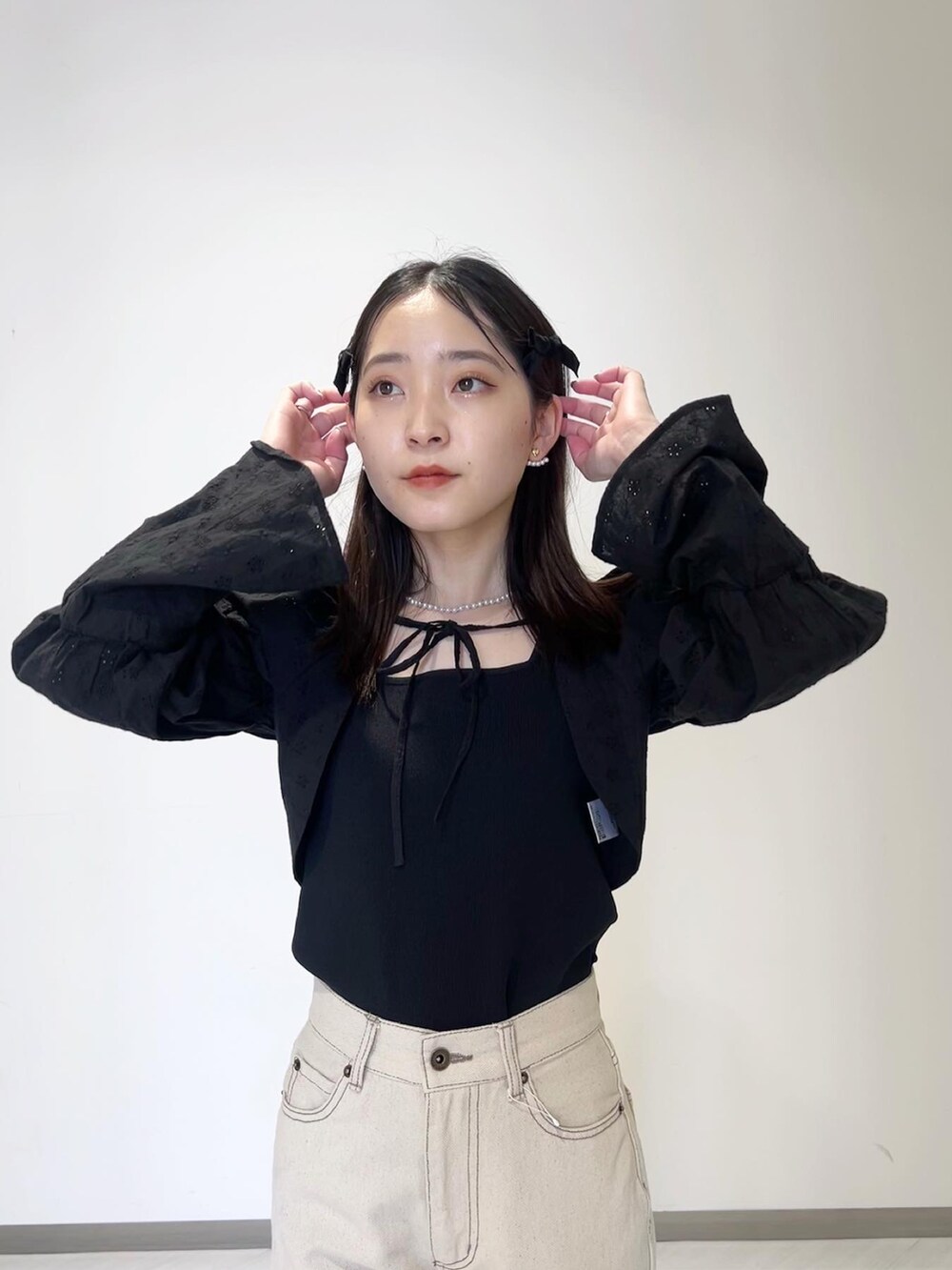 ブラック系のニット/セーター、ブラック系のカーディガン/ボレロ、ホワイト系のデニムパンツを着用したレディースの春コーディネートの5枚目の写真