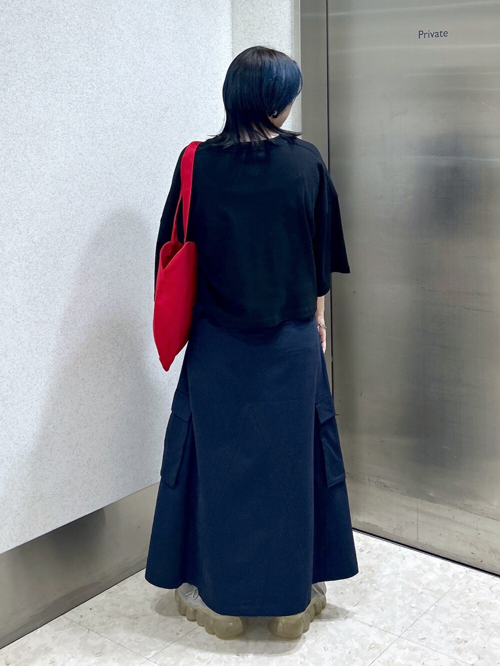 ブルー系のスカート、ブラック系のTシャツ/カットソー、レッド系のトートバッグを着用したレディースの夏コーディネートの5枚目の写真