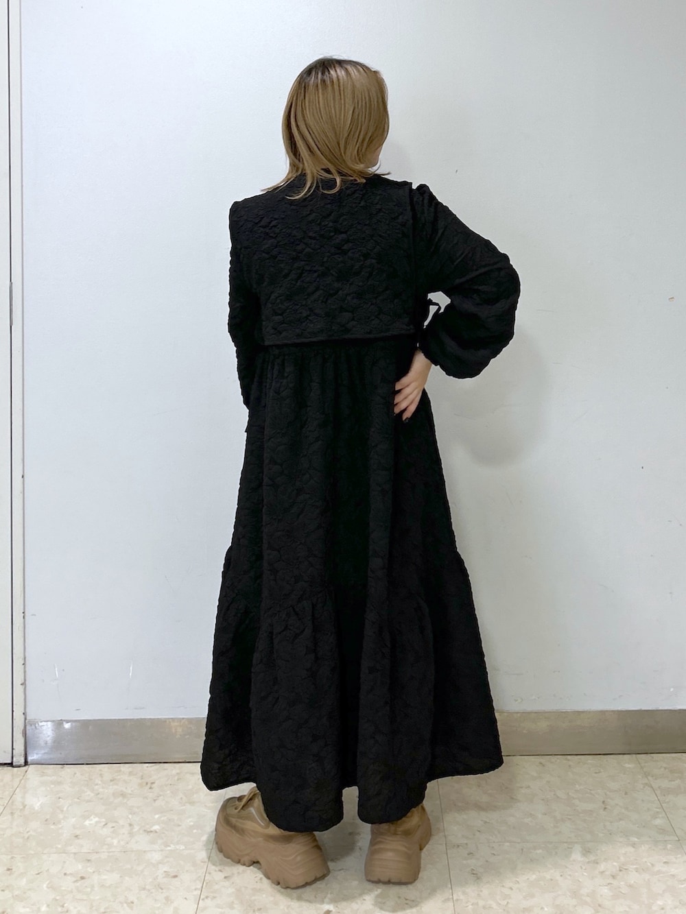 ブラック系のワンピース、パープル系のショルダーバッグ、ベージュ系のスニーカーを着用したレディースの冬コーディネートの2枚目の写真