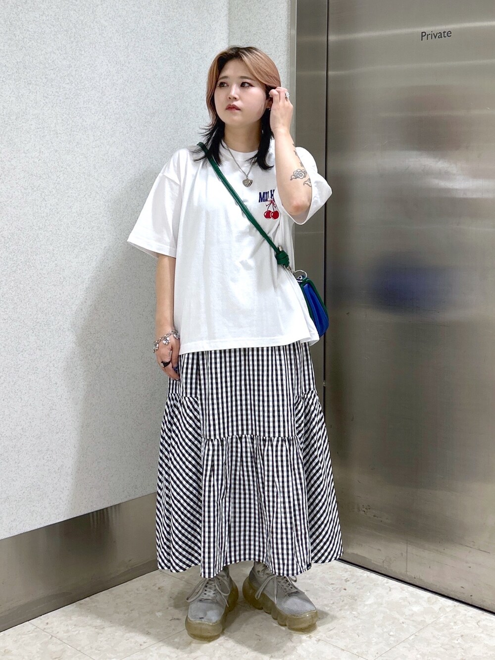 ホワイト系のTシャツ/カットソー、ブラック系のスカート、ブルー系のショルダーバッグを着用したレディースの夏コーディネートの2枚目の写真