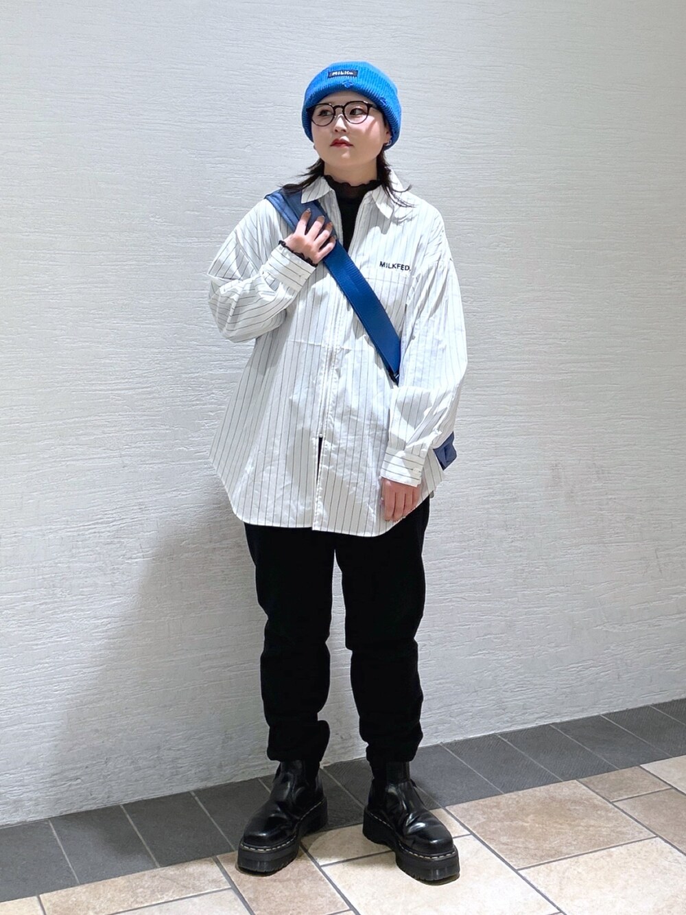 ホワイト系のシャツ/ブラウス、ブルー系のメッセンジャーバッグ、ブラック系のスウェットパンツを着用したレディースの冬コーディネートの3枚目の写真