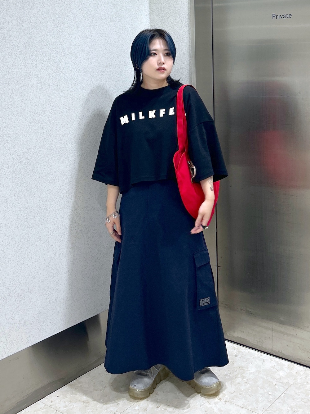 ブルー系のスカート、ブラック系のTシャツ/カットソー、レッド系のトートバッグを着用したレディースの夏コーディネートの2枚目の写真