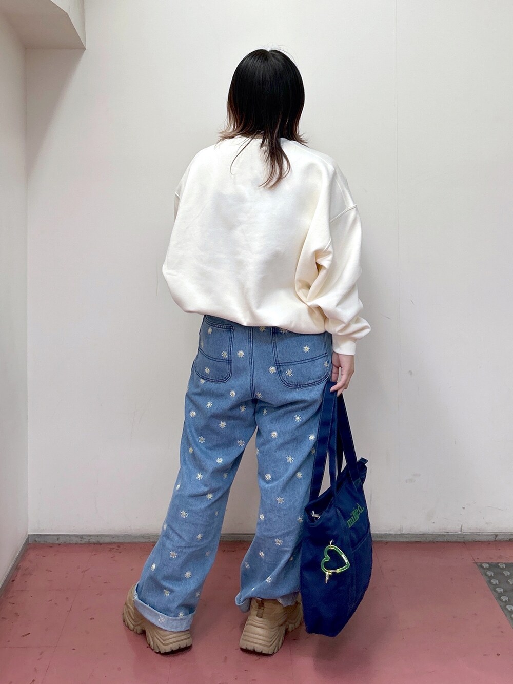 ホワイト系のスウェット、ブルー系のトートバッグ、ブルー系のデニムパンツを着用したレディースの秋コーディネートの3枚目の写真