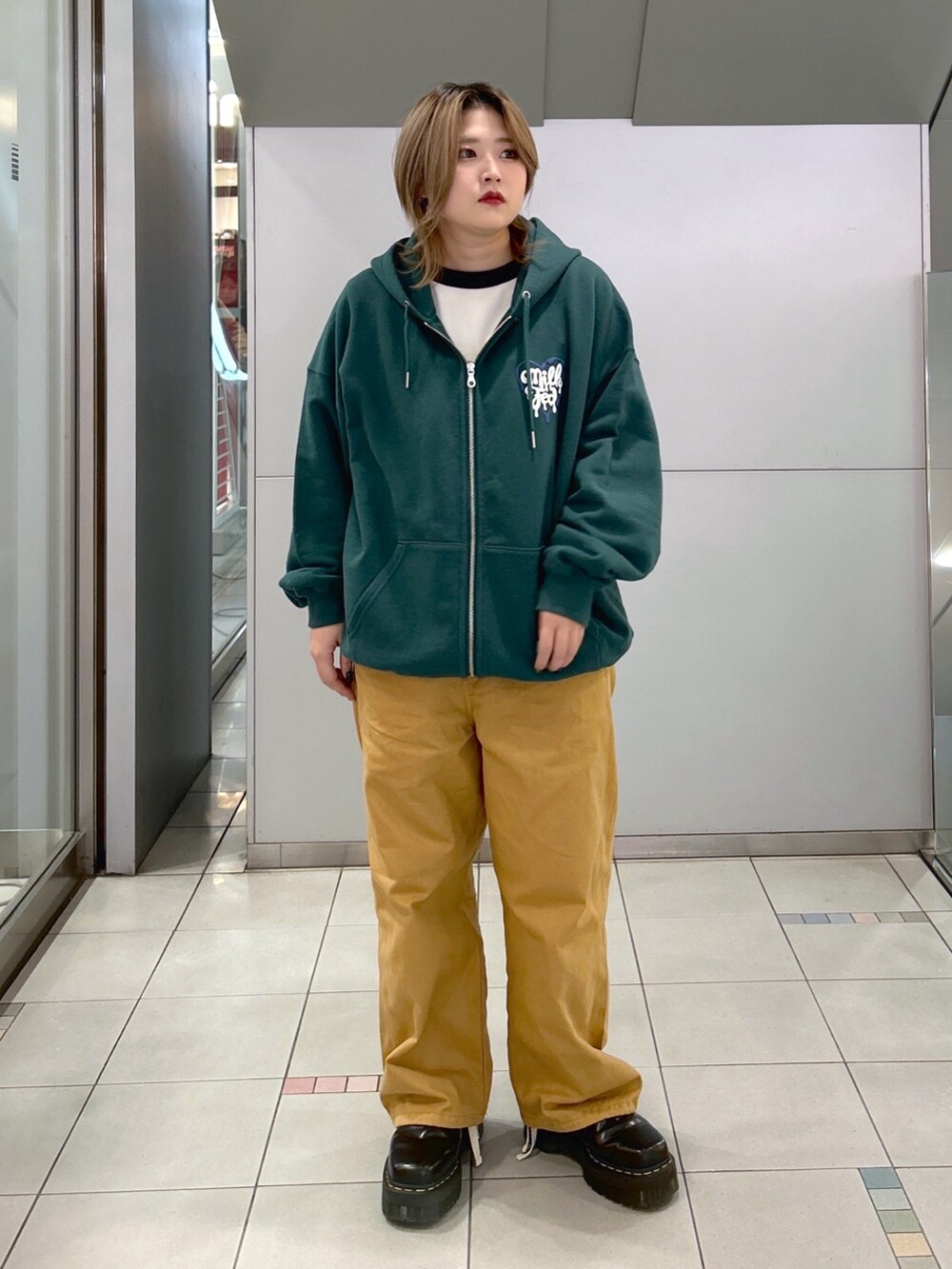 グリーン系のパーカー、ブラック系のTシャツ/カットソー、ベージュ系のサロペット/オーバーオールを着用したレディースの冬コーディネートの3枚目の写真