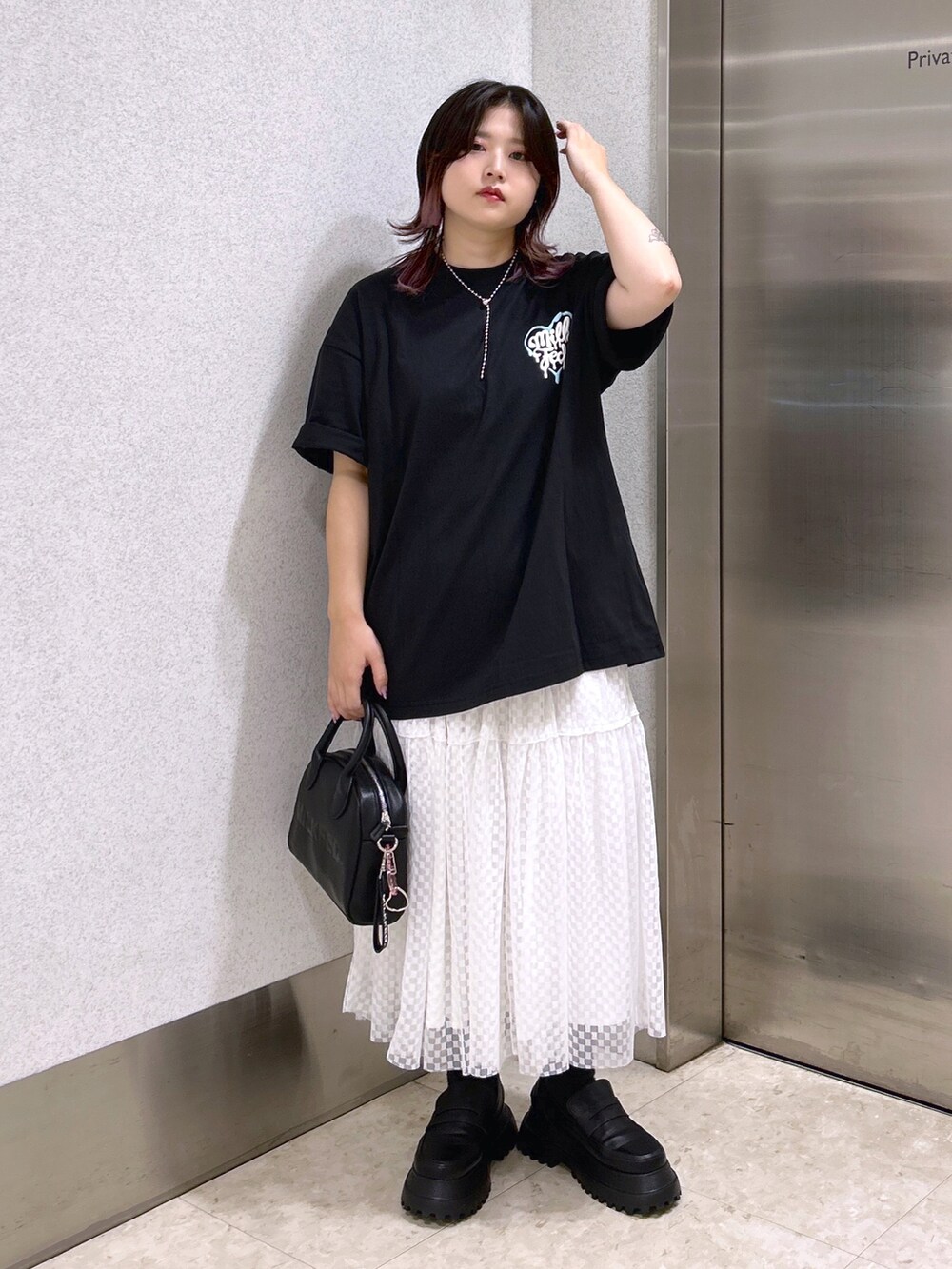 ブラック系のTシャツ/カットソー、ホワイト系のスカート、ブラック系のローファーを着用したレディースの夏コーディネートの2枚目の写真