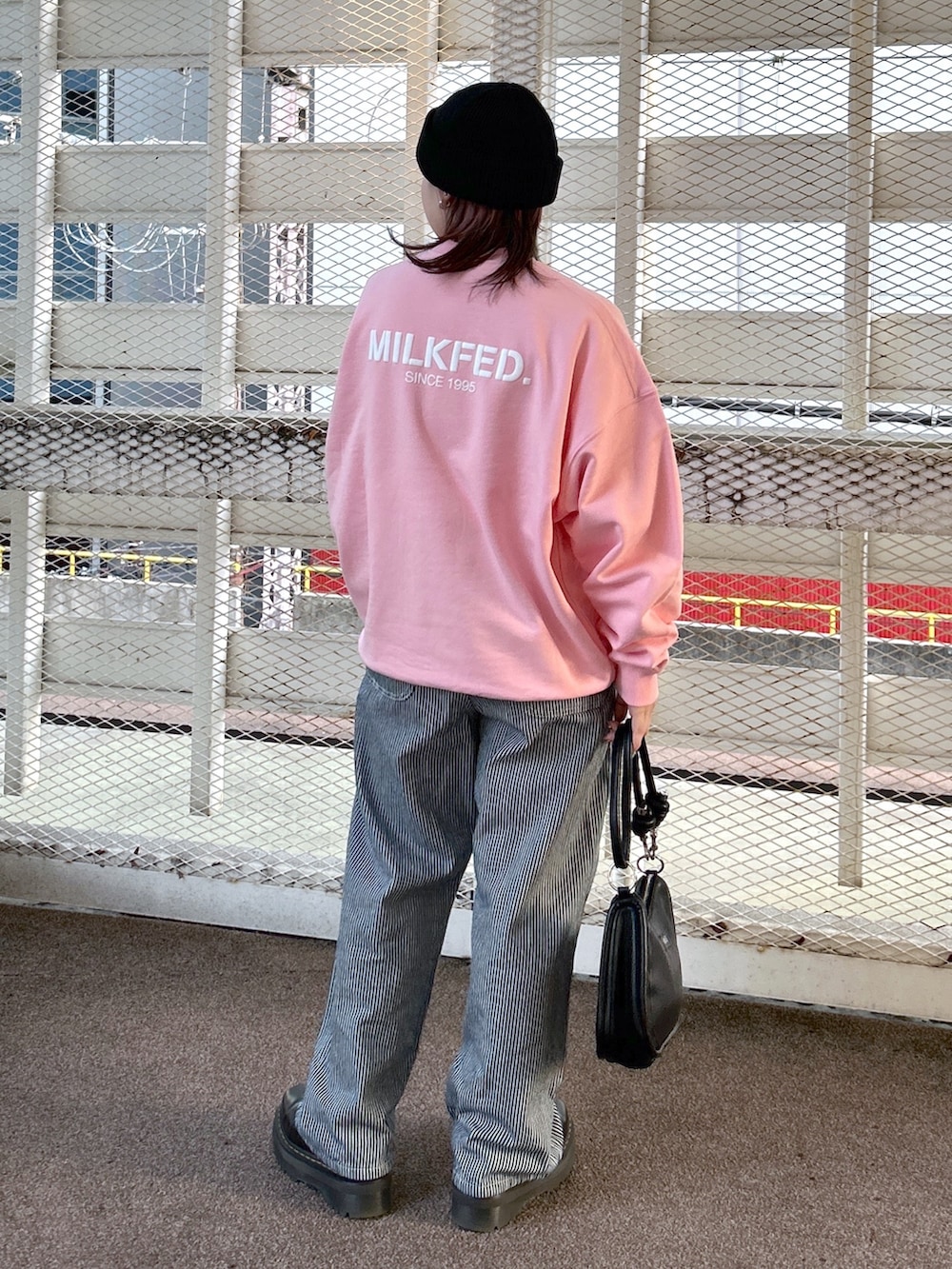 ピンク系のスウェット、ブラック系のショルダーバッグ、ブラック系のブーツを着用したレディースの冬コーディネートの3枚目の写真