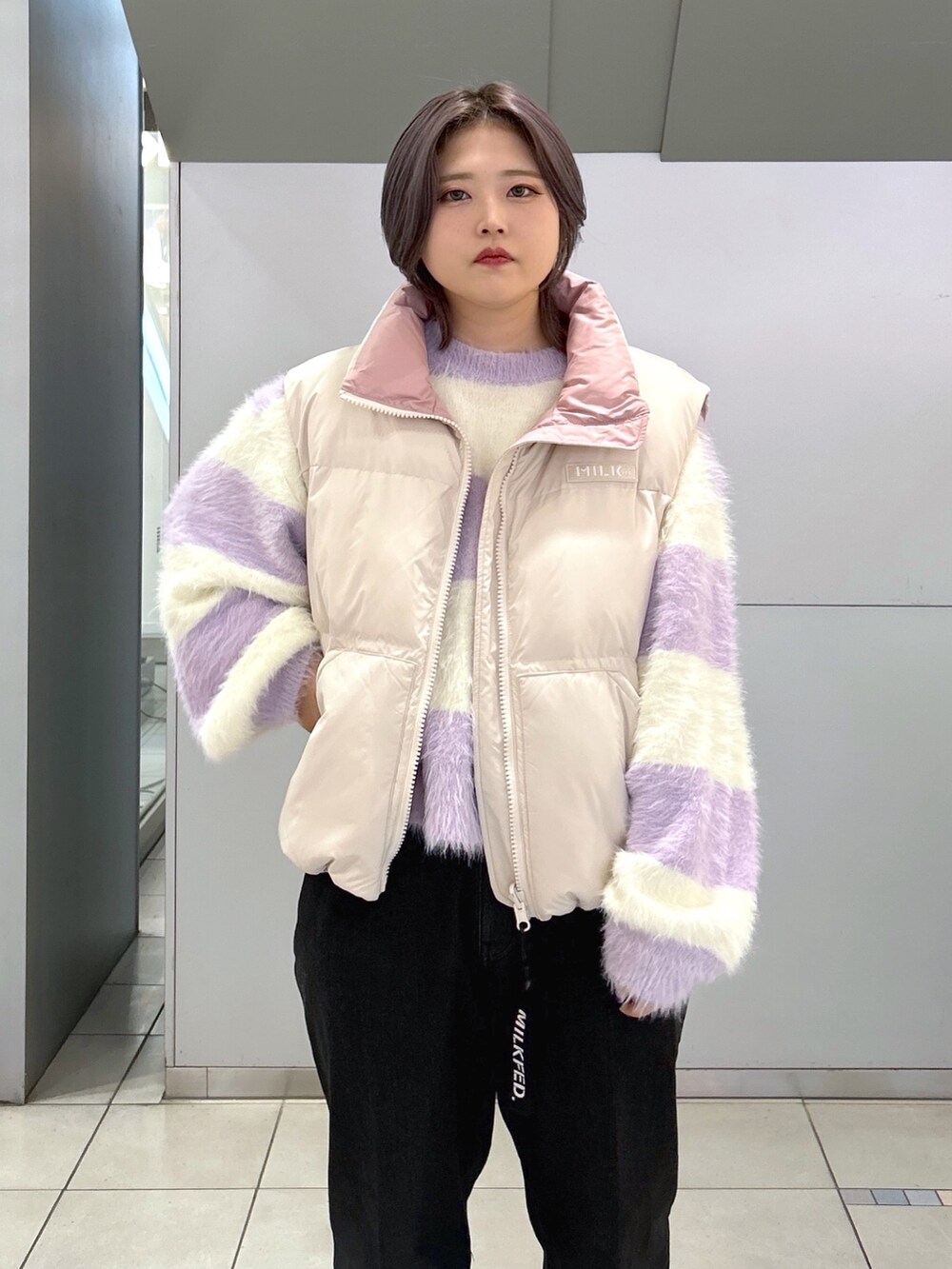 ブラック系のデニムパンツ、ベージュ系のスニーカー、ホワイト系のダウンベストを着用したレディースの秋コーディネートの4枚目の写真