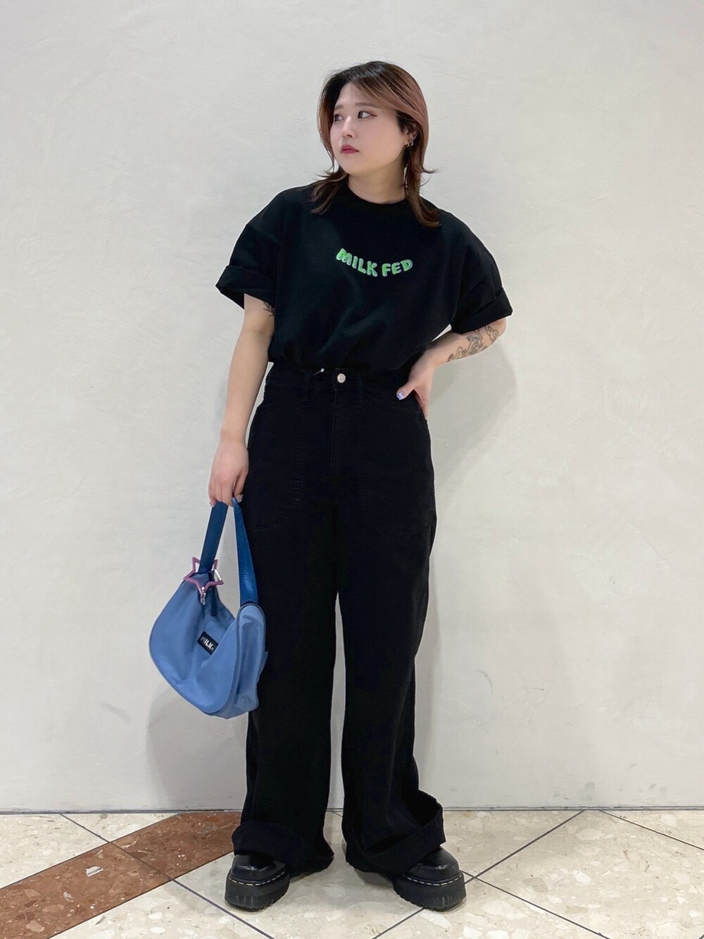 ブラック系のTシャツ/カットソー、ブルー系のハンドバッグ、ブラック系のブーツを着用したレディースの春コーディネートの2枚目の写真
