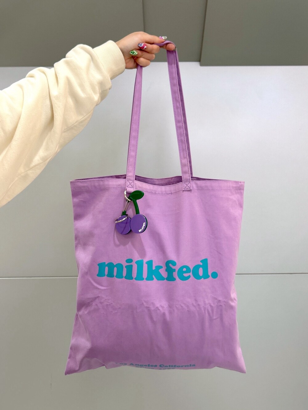 ホワイト系のスウェット、ブラック系のデニムパンツ、パープル系のトートバッグを着用したレディースの冬コーディネートの5枚目の写真