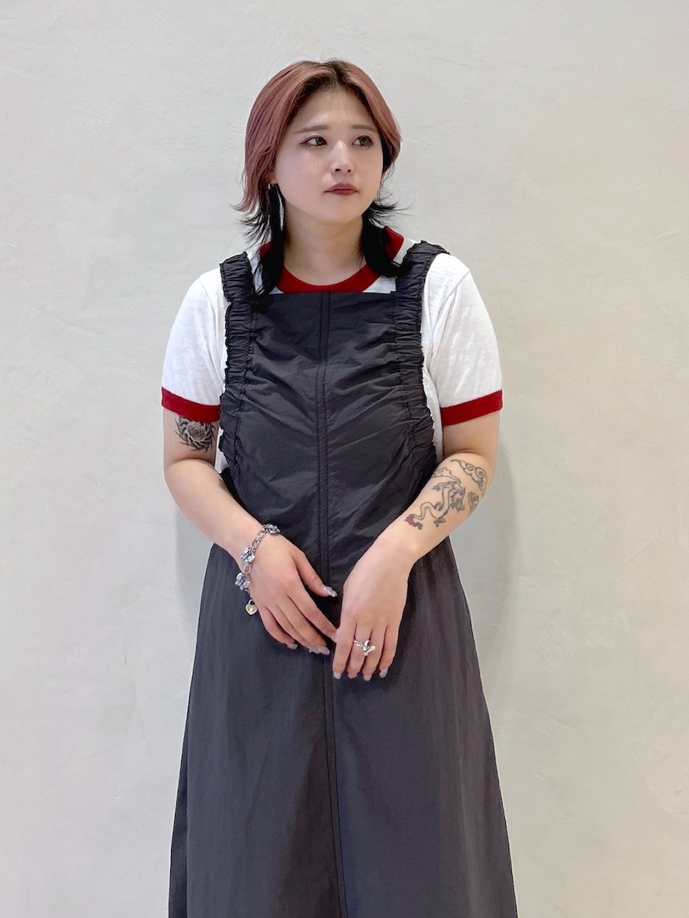 レッド系のTシャツ/カットソー、ベージュ系のサンダル、ブラック系のトートバッグを着用したレディースの春コーディネートの7枚目の写真