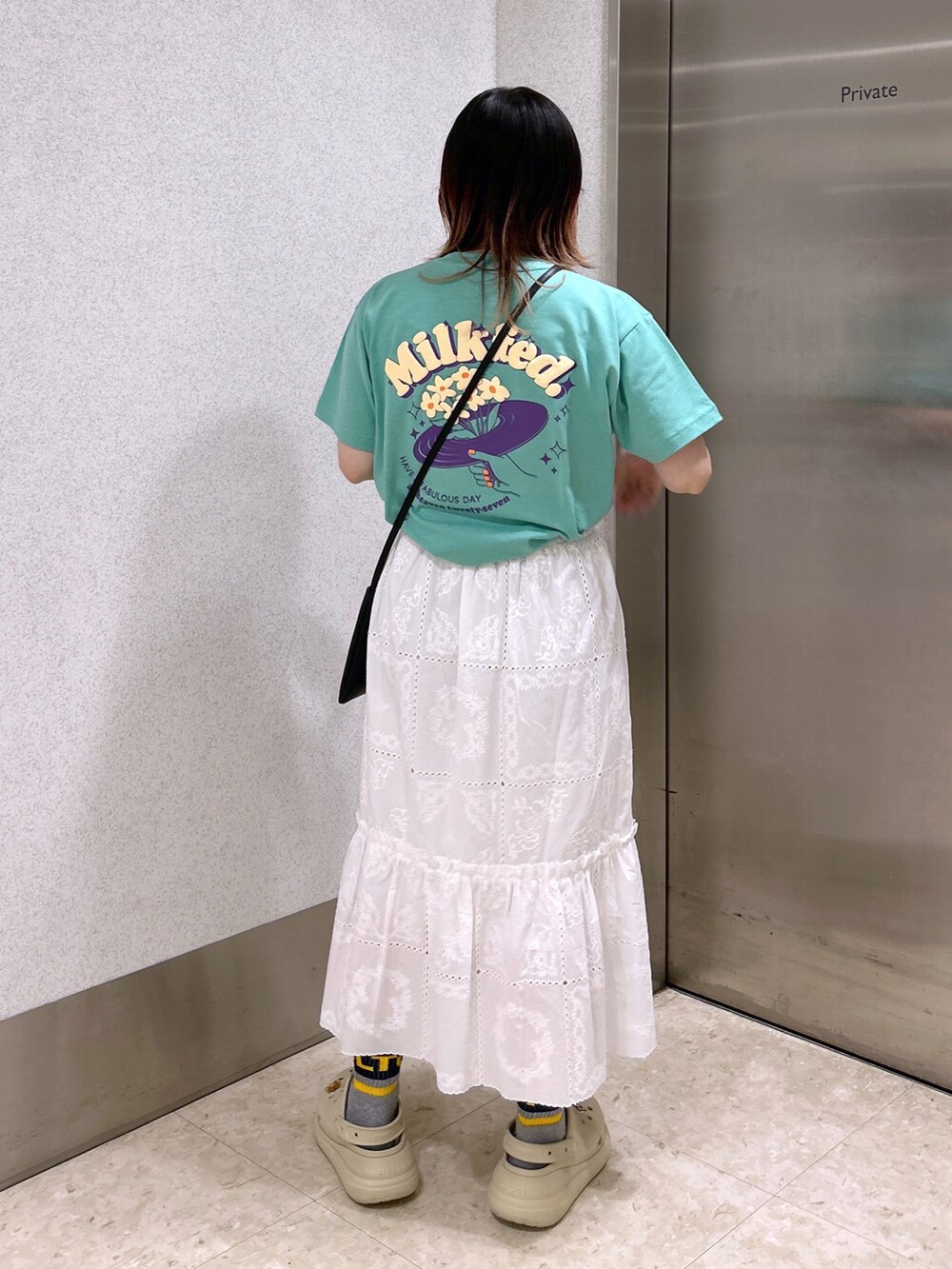 グリーン系のTシャツ/カットソー、ホワイト系のスカート、ベージュ系のサンダルを着用したレディースの夏コーディネートの2枚目の写真