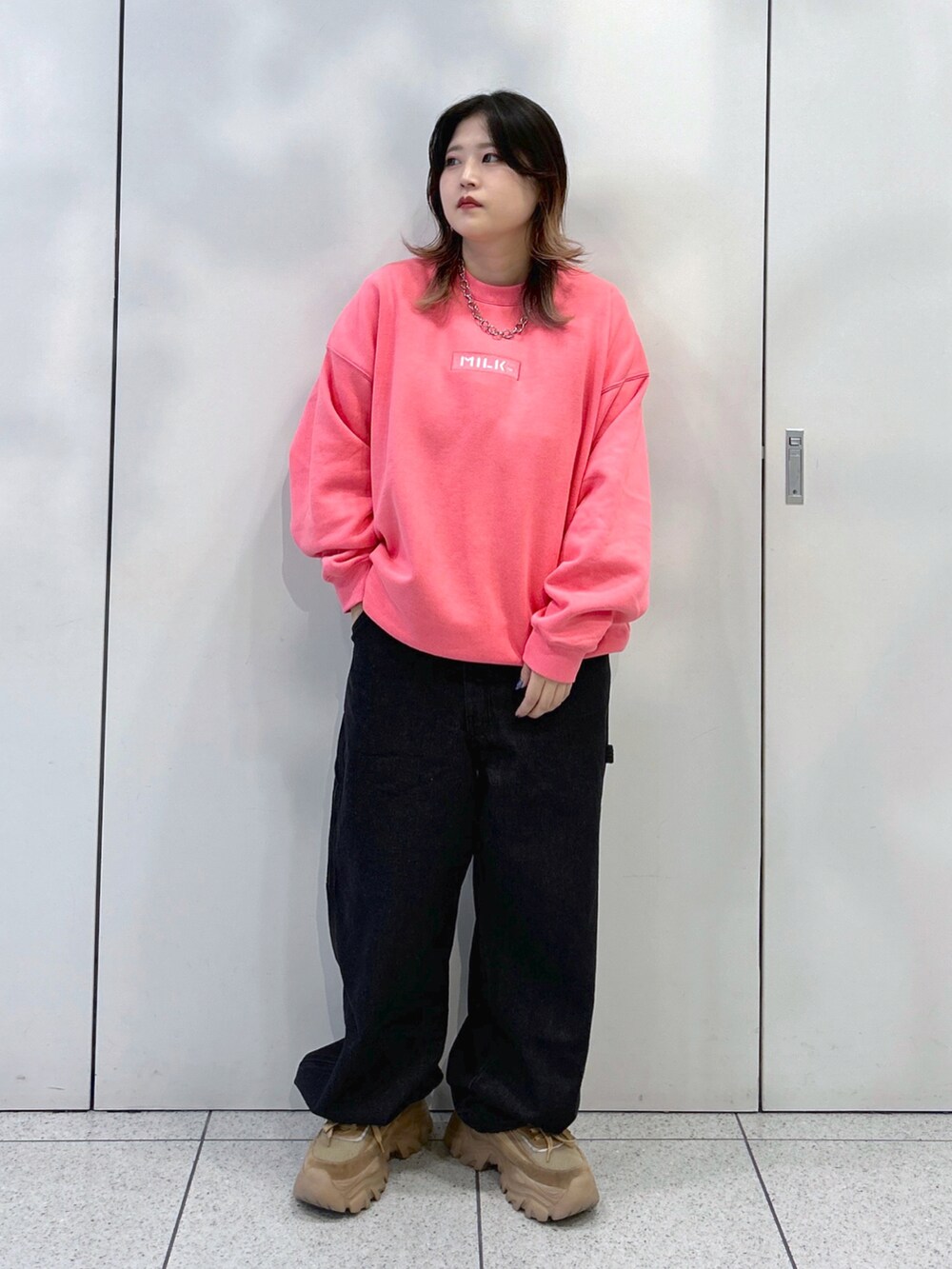 ピンク系のスウェット、ブラック系のサロペット/オーバーオール、ベージュ系のスニーカーを着用したレディースの秋コーディネートの2枚目の写真