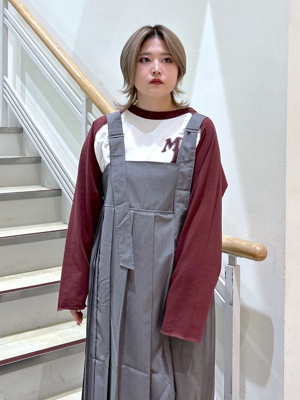 ブラウン系のTシャツ/カットソー、シルバー系のショルダーバッグ、グレー系のジャンパースカートを着用したレディースの秋コーディネートの3枚目の写真