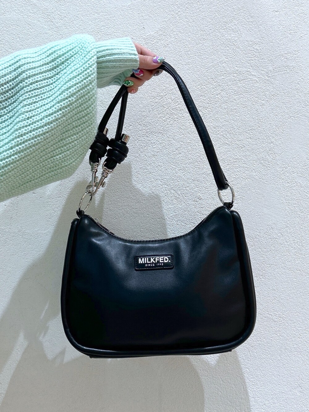 グリーン系のニット/セーター、ブラック系のショルダーバッグ、ブラック系のブーツを着用したレディースの冬コーディネートの7枚目の写真